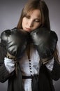 Creative portrait of a sad, tired businesswoman in boxing gloves. Gray background Royalty Free Stock Photo