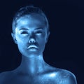 Creative portrait of surreal girl with glowing skin, blue tone in dark