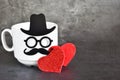 Creative postcard on Happy Fathers Day with funny face from cup of coffee, eyeglasses and mustache with two ref hearts on grey bac