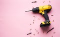 Creative provocation: a yellow screwdriver on a pink background and small screws. Royalty Free Stock Photo