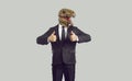 Funny businessman in humorous trendy dinosaur mask showing thumbs up on gray background.