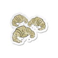 A creative retro distressed sticker of a cartoon croissants
