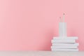 Creative school library - pile white blank books and white pencils on pink background.