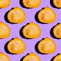 Creative seamless food pattern of halved orange pumpkin on neon purple background