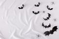 Creative season layout made of bats silhouettes and spiders on white fabric background with copy space