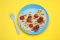 Creative serving for kids. Plate with cute octopuses made of sausages, pasta and vegetables on yellow table, flat lay Royalty Free Stock Photo