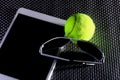 Creative Set Tennis ball, tablet computer and black sunglasses, close-up, on metal background.
