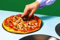 Creative slicing pizza. Female hands with italian pizza lying on vinyl discs on light tablecloth isolated on green