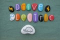 Drive Electric, modern transportation slogan with creative stones design over green sand