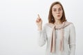 Creative smart excited attractive european female tutor in glasses with pullover tied over neck raising index finger in