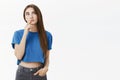 Creative smart and thoughtful attractive european woman in trendy blue cropped top making hmm gesture with finger on