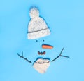 Creative snowman shape made of different items on light blue background, flat lay