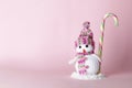 Creative snowman with sweet candy cane on a pink background