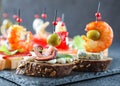 Creative Spanish tapas and seafood sandwich with octopus, olive on a slice of sesame bread with basil leaf and cream cheese for a