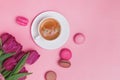 Creative spring composition with coffee, tulips and french dessert macarons on pink background Royalty Free Stock Photo