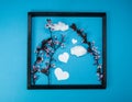 Creative spring composition made of cherry blossom tree branches and wooden picture frame on blue background with heart shape and Royalty Free Stock Photo