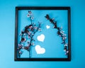 Creative spring composition made of cherry blossom tree branches and wooden picture frame on blue background with heart shape, spr Royalty Free Stock Photo