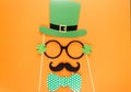 Creative st Patricks Day orange background. Flat lay composition of Irish holiday celebration with photo booth decor: hat, glasses