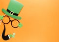Creative st Patricks Day orange background. Flat lay composition of Irish holiday celebration with photo booth decor: hat, glasses
