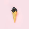 Creative still life of black ice cream in waffle cone on pink background. Spring concept. Top view. Royalty Free Stock Photo