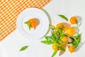 Creative still life composition made of fresh orange mandarin fruits on white background with cage kitchen towel and a plate. Royalty Free Stock Photo