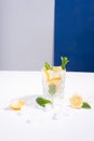 creative summer cocktail with ice in a glass glass with lemon, mint and ice cubes on a white-blue background Royalty Free Stock Photo