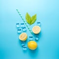 Creative summer composition with sliced lemon, straw and ice cubes on blue background. Minimal drink concept Royalty Free Stock Photo