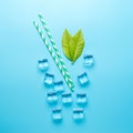 Creative summer composition with straw and ice cubes on blue background. Minimal drink concept Royalty Free Stock Photo