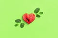 Creative summer food concept. Juicy slices of ripe red watermelon in the shape of a heart and mint leaves on green background.
