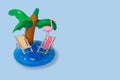 Creative summer idea with inflatable palm ring, deck chairs and exotic flamingo bird on pastel blue background