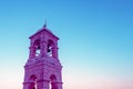 Creative surreal purple bell tower on blue sky background, the concept of modern religion