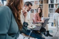 Multi generational people collaborating in a bright office setting, engaged in discussion with laptops, exuding a Royalty Free Stock Photo