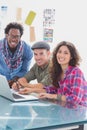 Creative team working together on laptop and smiling at camera Royalty Free Stock Photo