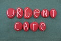 Urgent Care, medical text composed with red colored and carved stone letters over green sand
