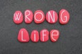 Wrong life text composed with red colored stone letters over volcanic sand