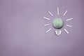 Creative thinking ideas and innovation concept. A mint color ball threads with a light bulb symbol on a violet