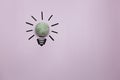Creative thinking ideas and innovation concept. A mint color ball threads with a light bulb symbol on a violet background