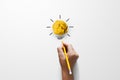 Paper scrap ball yellow colour with light bulb symbol on white background and hand holding yellow pencil Royalty Free Stock Photo