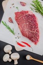 Creative Top view flat lay of fresh raw beef meat striploin steak with rosemary thyme herbs garlic pepper mushrooms on black Royalty Free Stock Photo