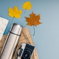 Creative Top view flat lay outdoors trip composition. Thermos map retro camera cutlery blanket grey blue background copy space.