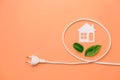 Creative top view flat lay of paper white house, electrical plug, little green leaves, mockup composition with copy space