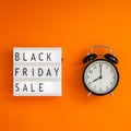 Creative Top view flat lay promotion composition Black friday sale text on lightbox alarm clock orange background copy space