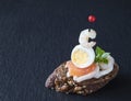 Creative traditional food - Spanish tapas on a black serving board. Tapas are made with seafood - salmon, shrimp, squid, quail egg