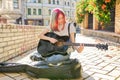 Creative female playing acoustic guitar sitting on sidewalk with guitar case and cash Royalty Free Stock Photo