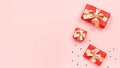 Creative Valentine`s Day greeting card with red decorations and gift boxes, golden heart confetti on pink background, copy space, Royalty Free Stock Photo