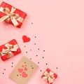 Creative Valentine`s Day greeting card with red decorations and gift boxes, golden heart confetti on pink background, copy space, Royalty Free Stock Photo