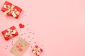 Creative Valentine`s Day greeting card with red decorations and gift boxes, golden heart confetti on pink background, copy space, Royalty Free Stock Photo