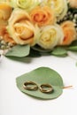 Creative wedding rings on green leaf, blurred cream colored roses Royalty Free Stock Photo