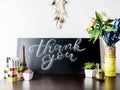 Creative White and blue Chalk Lettering Thank you on chalkboard on table with plants, flowers and art objects in home interior. Th Royalty Free Stock Photo