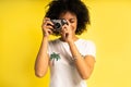 Creative woman-photographer takes photos, isolated on yellow.